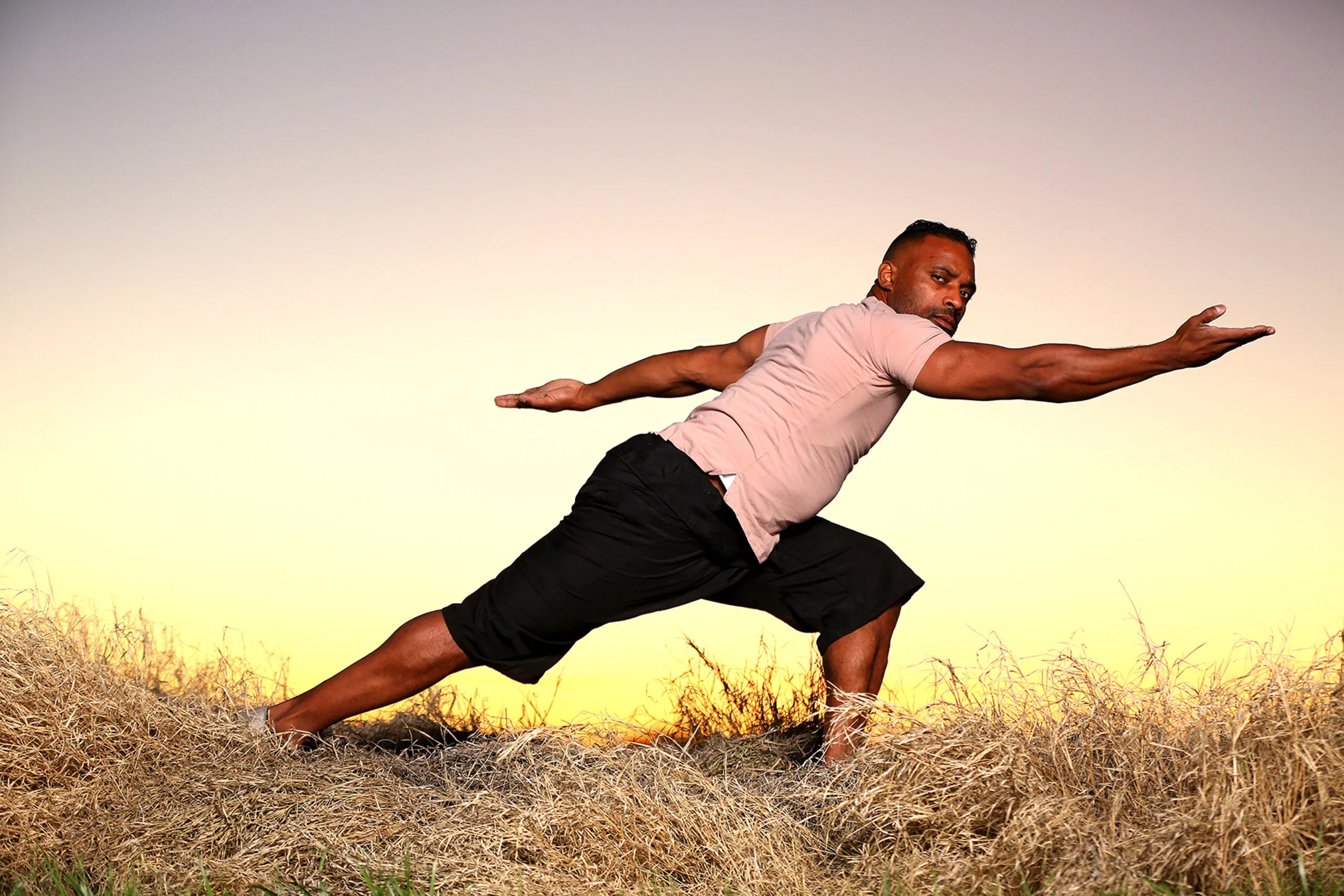 Demaris Parker performing a Qigong form against a golden sunset